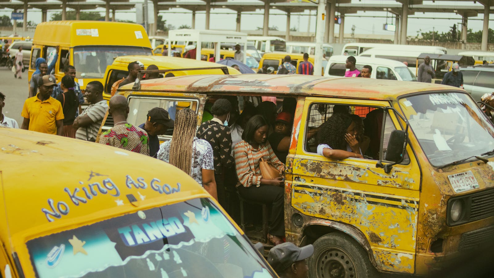 Yellow danfo buses on a busy Lagos street with commuters